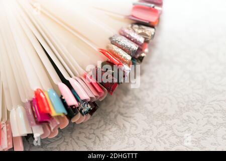 Eine Sammlung von mehrfarbigen Plastiknagelproben für die Maniküre liegt wie ein Fächer auf dem Tisch. Stockfoto