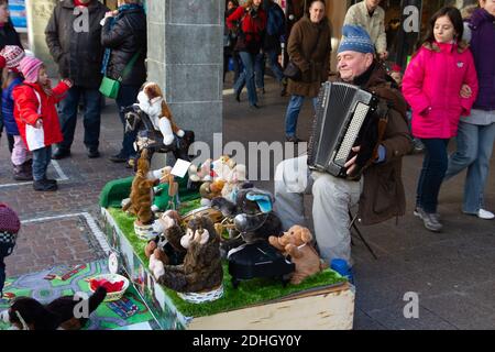 Freiburg im Breisgau, Deutschland - 11 09 2012: Ein alter Mann mit lustigen Plüschspielzeugen spielt auf der Straße vor der Mall die Ziehharmonika. Folklore, Straße Stockfoto