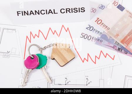 Schlüssel des Hauses, Währungen Euro, Abwärtsgraphen und Inschrift Finanzkrise auf elektrischen Baudiagrammen. Immobilienkrise Stockfoto