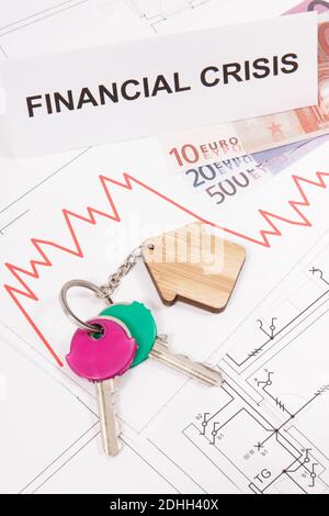 Schlüssel mit Home Form, Währungen Euro, Abwärtsgraphen und Inschrift Finanzkrise auf elektrischen Baudiagramme des Hauses. Immobilien-Kris Stockfoto