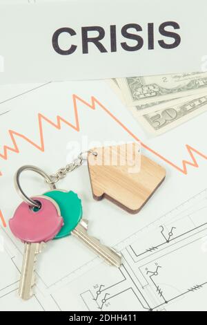 Schlüssel des Hauses, Währungen Dollar, Abwärtsgraphen und Inschrift Krise auf elektrischen Baudiagrammen. Immobilienkrise Stockfoto