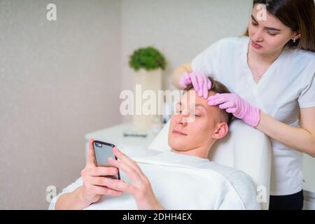 Männliche Kosmetik. Ein gut aussehender Mann, der im luxuriösen Spa eine Gesichtsbehandlung bekommt Stockfoto
