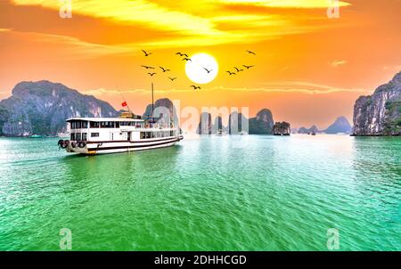 Dreamy sunset in Halong bay, Vietnam. Tourist cruise ship floating among limestone rocks. This is the UNESCO World Heritage Site, Stock Photo