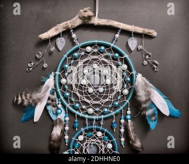 Nahaufnahme eines schönen Boho-Styled-Traumfängers mit blauen Federn und Perlen gegen Schwarz. Mystischer Hintergrund mit Traumfänger, esoterisch und okkult Stockfoto