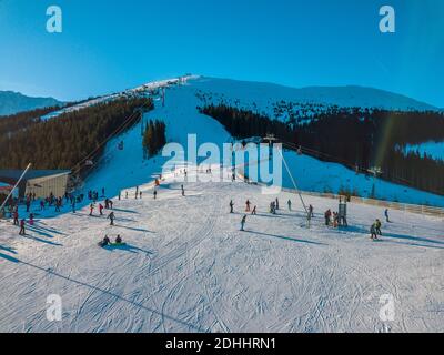 Slowakei. Winter Jasna in sonnigen Tag. Skipisten in den bewaldeten Bergen. Blauer Himmel und Sonne scheint hell. Luftaufnahme Stockfoto