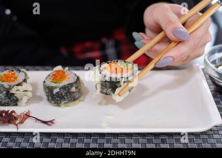 Gunkan Sushi mit Lachsrogen auf einem weißen Teller mit japanischen Essstäbchen. Stockfoto