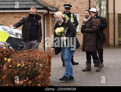 Eine Frau stellt Blumen an die Szene eines Hausfeuers auf Buttercup Avenue, Eynesbury, Cambridgeshire, in dem ein dreijähriger Junge und ein siebenjähriges Mädchen starben. Auch eine 35-jährige Frau und eine 46-jährige wurden bei dem Brand im dreistöckigen Haus verletzt, von dem die Polizei glaubt, dass er gegen 7 Uhr morgens am Donnerstagmorgen ausbrach. Stockfoto