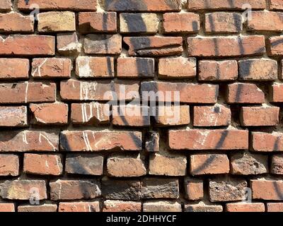 Eine alte rote Ziegelwand mit schwarzer Farbe besprüht Stockfoto