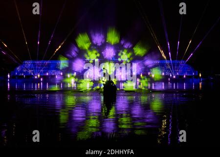 Ein Blick auf das 'Palm House Grand Finale', das festliche Projektionen beinhaltet, die während der Weihnachtszeit im Kew im Royal Botanic Gardens in Kew, London, auf einen riesigen Bildschirm mit Wasser im See fallen. Stockfoto