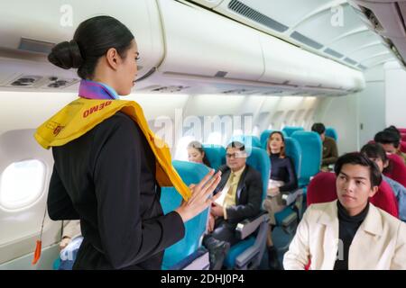 Asian Air Hostess Mitarbeiter Fluggesellschaft demonstrieren Sicherheitsverfahren für Passagiere vor dem Abflug im Kabinenflugzeug. Stockfoto