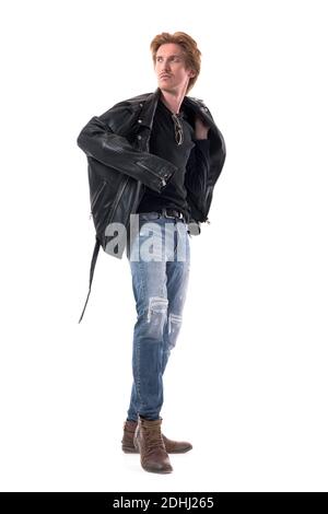 Schöner junger Rotschopf Mann zog auf schwarze Lederjacke in zerrissenen Jeans Blick hinter. Ganzkörperlänge isoliert auf weißem Hintergrund. Stockfoto