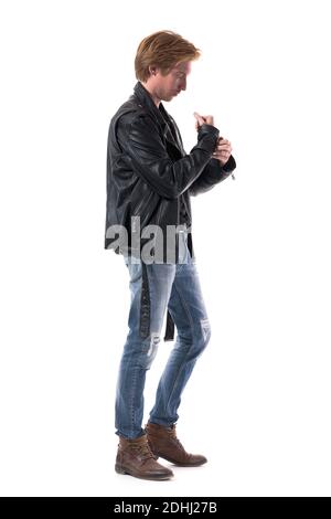 Seitenansicht der stilvollen Mann in Biker-Stil Kleidung immer angezogen Knopfjacken Ärmel. Ganzkörperlänge isoliert auf weißem Hintergrund. Stockfoto