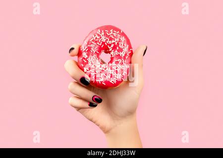 Womans Hand hält bunte Donut über rosa Hintergrund. Modell Vorlage für Bäckerei Stockfoto