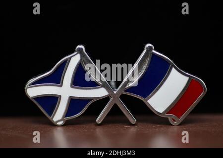Schottischer Saltyre und französische Flagge Lapel Pin Abzeichen auf Holz Basis und schwarzer Hintergrund Stockfoto