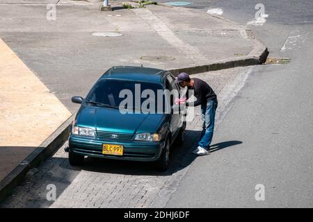 MEDELLIN, KOLUMBIEN - 03. Dezember 2020: Medellin, Antioquia, Kolumbien - 2. Dezember 2020: Junger Venezolaner hält ein Auto an, um Süßigkeiten auf der Straße zu verkaufen Stockfoto