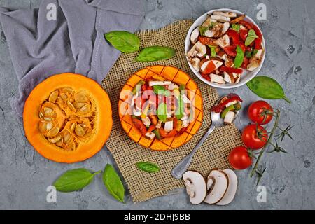 Gebackenes veganes rotes Kürbisgemüse mit Paprika, Tomaten und Pilzen, umgeben von Zutaten Stockfoto