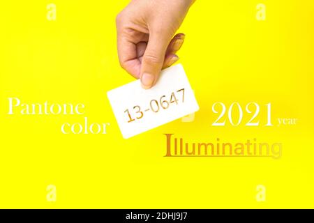 Pantone Farbe des Jahres 2021. Visitenkarte in der Hand mit Text 13-0647, beleuchtet auf gelbem Hintergrund. Farbtrend. Leuchtet Stockfoto