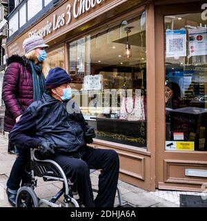 Kingston London UK, Dezember 09 2020, älterer behinderter Mann im Rollstuhl, der im Schaufenster mit Pfleiher schaut Stockfoto