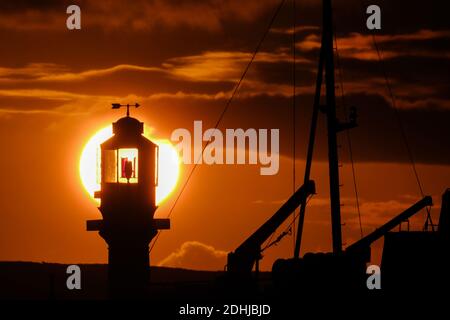 Die Ruhe vor Storm Alex, wenn die Sonne hinter dem Penzance Harbour Leuchtturm am ersten Oktobertag aufgeht. Stockfoto