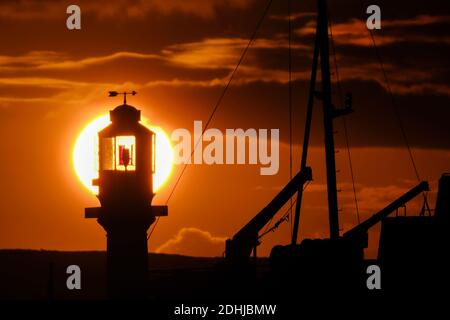 Die Ruhe vor Storm Alex, wenn die Sonne hinter dem Penzance Harbour Leuchtturm am ersten Oktobertag aufgeht. Stockfoto