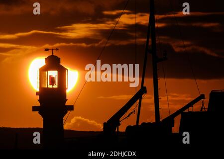 Die Ruhe vor Storm Alex, wenn die Sonne hinter dem Penzance Harbour Leuchtturm am ersten Oktobertag aufgeht. Stockfoto