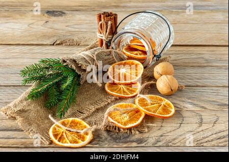 Weihnachtskomposition mit Fichtenzweigen, Zimtstangen und Girlande aus getrockneten Orangenscheiben auf Holzhintergrund. Rustikaler Stil Stockfoto