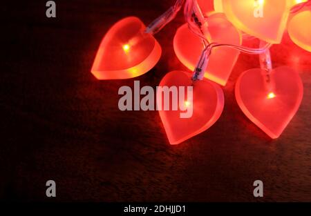 Beleuchtete rote Herzlichter auf dunklem Hintergrund Stockfoto