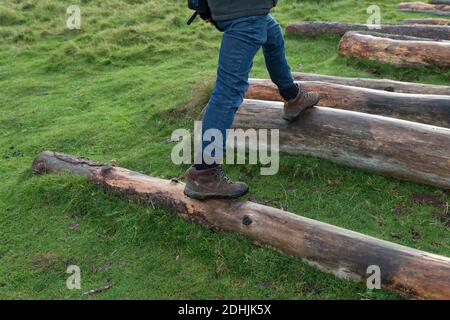 Nahaufnahme der Beine und Füße des Menschen, die draußen in Wanderschuhen auf Holzstämmen treten. Männlich Wandern im Freien unter Bewegung im Winter Stockfoto