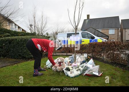 Eine Frau stellt einen Teddybären mit anderen Tributen an die Szene eines Hausfeuers auf Buttercup Avenue, Eynesbury, Cambridgeshire, wo ein dreijähriger Junge und ein siebenjähriges Mädchen starben. Auch eine 35-jährige Frau und eine 46-jährige wurden bei dem Brand im dreistöckigen Haus verletzt, von dem die Polizei glaubt, dass er gegen 7 Uhr morgens am Donnerstagmorgen ausbrach. Stockfoto