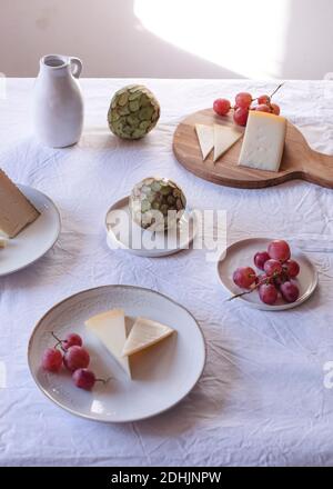 Hoher Winkel von verschiedenen schmackhaften Käse auf dem Tisch mit angeordnet Anona Früchte und Trauben in der Nähe von Keramik-Krug Stockfoto