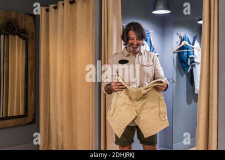 Vorderansicht des Mannes, der Hosen in der Kleidung überprüft Zimmer eines Bekleidungsladens Stockfoto