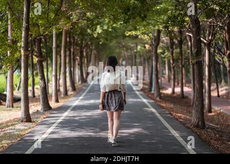 Rückansicht anonymer Frauen im Sommer-Outfit beim Spazierengehen Pfad in Tanya Shen Green Radweg Stockfoto
