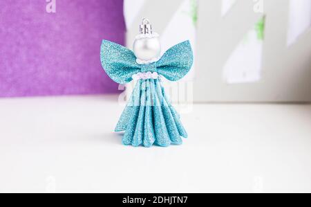 DIY weihnachtsengel. Blauer Schaumstoffengel auf violettem Hintergrund. Handgemachte weihnachtsdekoration. Stockfoto