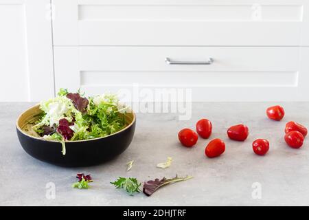 Salat grüne Blätter in Schüssel in Tisch mit frischen gelegt Tomaten Stockfoto