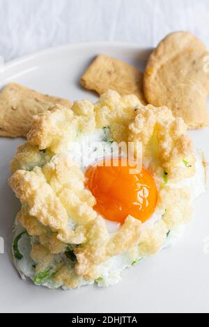 Hoher Winkel von appetitlich hausgemachten gebackenen Wolke Eier mit grün Gemüse serviert mit knusprigen Crackern für ein gesundes Frühstück Stockfoto