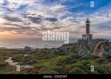 Malpica, Galicien / Spanien - 26. November 2020: Sonnenuntergang am Leuchtturm Punta Nariga in Galicien mit einem grauen Wohnmobil, der dort geparkt ist Stockfoto