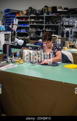 Weibliche Arbeiterin in bei Gepäckhersteller Samsonite näht mit Nähmaschine, Mansfield, Massachusetts, USA. Stockfoto