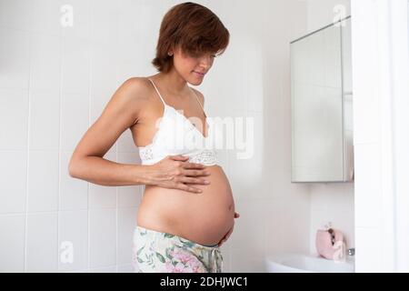 Crop bärtige männliche Spezialist trägt weiße Robe und Handschuhe Notizen machen und überprüfen grünen Hanf Pflanzen mit dünnen Blättern, während der Arbeit im Gewächshaus in Stockfoto