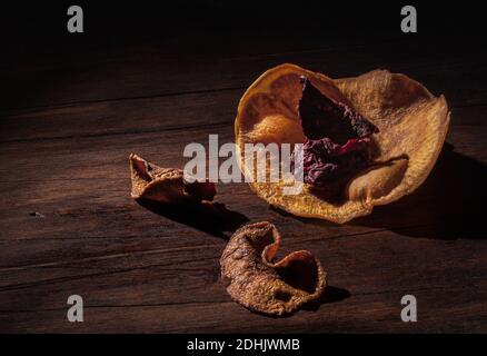 Stillleben Chiaroscuro Zusammensetzung mit dehydrierten geschnittenen Süßkartoffeln und Die Rübe ist in Form der Blume auf der hölzernen Oberfläche angeordnet Stockfoto