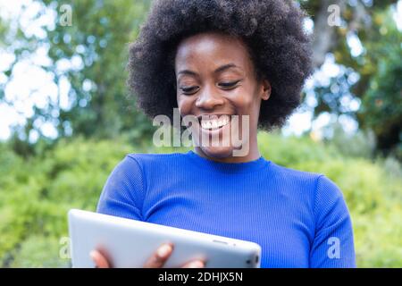 Inhalt Afrikanisch-amerikanische Freiberuflerin sitzt auf der Bank im Park Und mit Tablet arbeiten, während Remote auf Startup-Projekt Stockfoto