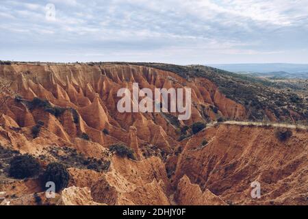 Von oben erstaunliche Landschaft von Sandstein felsigen Formationen mit unebenen Oberfläche durch Erosion unter blauem bewölktem Himmel im Hochland verursacht Stockfoto