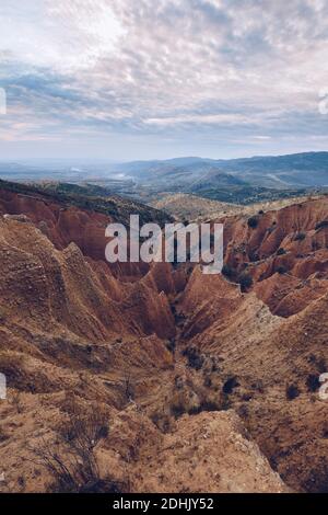 Von oben erstaunliche Landschaft von Sandstein felsigen Formationen mit unebenen Oberfläche durch Erosion unter blauem bewölktem Himmel im Hochland verursacht Stockfoto