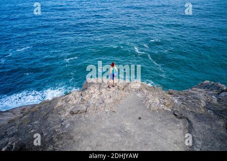 Von oben der anonymen weiblichen Touristen, die auf Felsen und stehen Genießen Sie den Blick auf das türkisfarbene Meer während des Sommerurlaubs Stockfoto