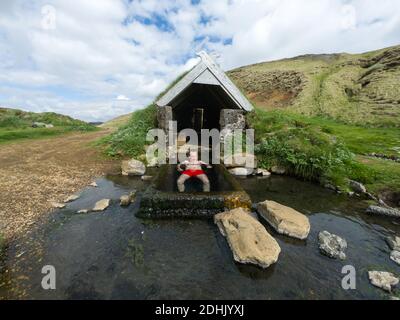 Mann in einem kleinen geothermischen Thermalbad in Hrunalaug, Island entspannen Stockfoto