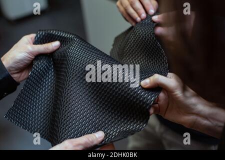 Nahaufnahme der Hände zur Überprüfung der Materialqualität am Produktionsstandort von Samsonite in Oudenaarde, Belgien Stockfoto
