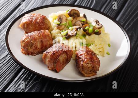 Slavink ist Hackfleisch, in Speck eingewickelt und in Butter und Schmalz gebraten serviert mit Kartoffelpüree und Pilzen in der Nähe auf dem Teller auf dem Tisch. hor Stockfoto