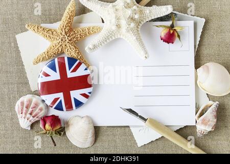 Postkarte mit Platz für Ihre Grüße, Muscheln um. Die Flagge von Großbritannien, allgemein bekannt als Union Jack auf Knopf Abzeichen gedruckt. Stockfoto