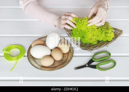 Floristen bei der Arbeit: Wie man Ostereier mit Moos und Bändern verziert. Frühlingsdekor-Ideen. Schritt für Schritt, Tutorial. Stockfoto