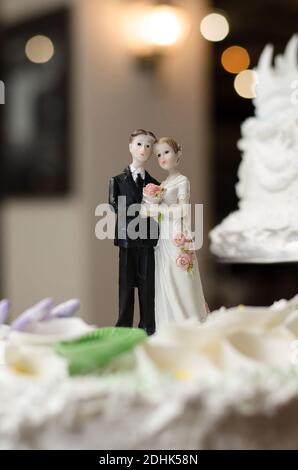 Figuren der Braut und des Bräutigams auf dem Hochzeitstorte. Mit unscharfem Hintergrund und Bokeh Stockfoto