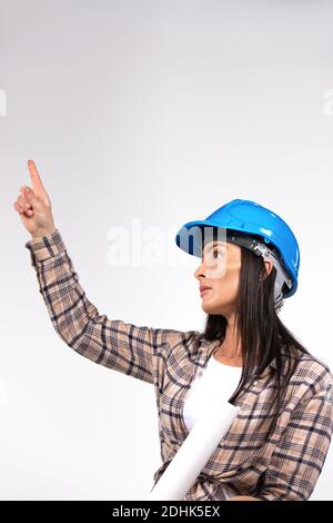 Frau Architektin in Hut schaut nach oben und zeigt mit Zeigefinger nach oben. Ort für Werbung. Weißer Hintergrund. Stockfoto
